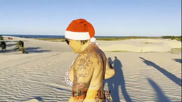 Naughty Santa Claus tattooed woman on sandy beach