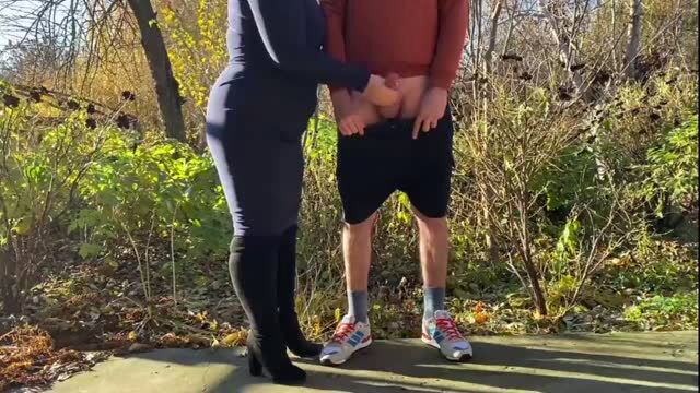 Mature woman in bodysuit exposes older man's penis outdoors
