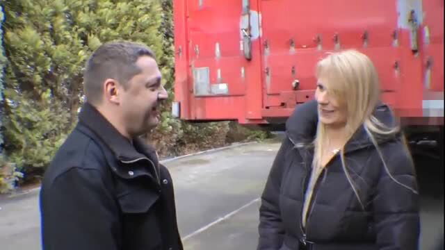 Blonde woman in puffy jacket talking to smiling man by red truck
