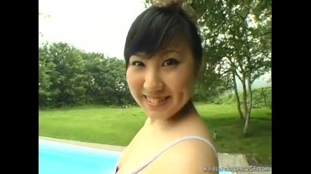 Cute Asian teen in bikini smiling by pool