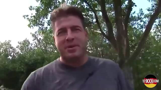 Man in grey t-shirt giving instructions outdoors before explicit scene