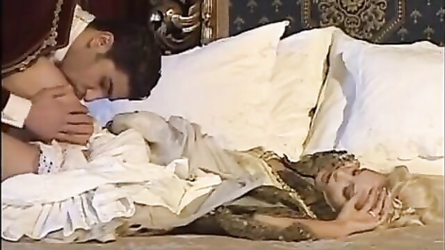Handsome musketeer passionately kisses busty blonde noblewoman in bed