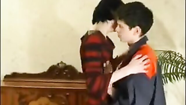 Older Russian man kissing young twink in striped shirt and orange top