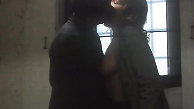 Passionate midnight kiss between suited man and woman in dim light