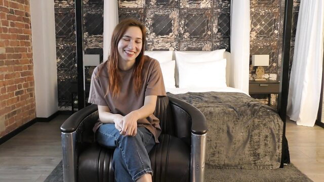 Smiling redhead teen in tee and jeans sits in chair, virgin caboose interview