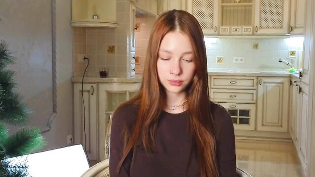 Redhead camgirl with sleepy eyes sits topless in kitchen, live show