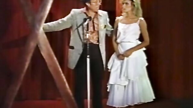 Vintage kinky couple: sexy blonde teen in white dress with older man on stage