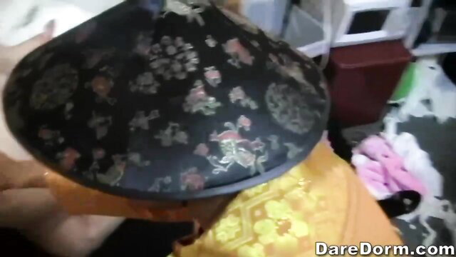 Brittany Angel in ornate Asian conical hat and yellow dress closeup