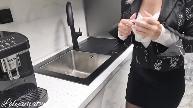 Hot Asian stepmom in blazer and skirt holding cup by kitchen sink