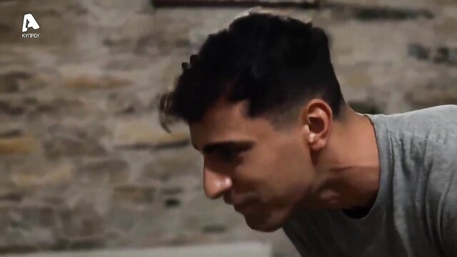 Handsome Greek guy with fade haircut in tight gray tee, profile view