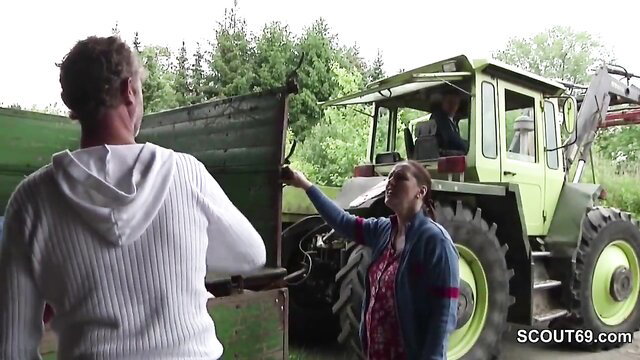 German MILF in dress points at green tractor in outdoor cuckold scene