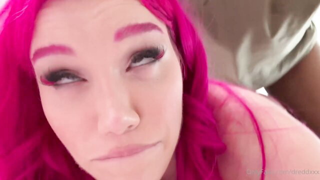 Pink-haired Lily Lou closeup face with intense gaze in explicit scene