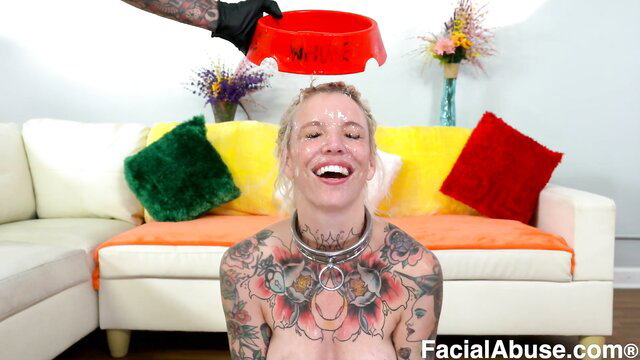Kitt Jones tattooed blonde smiles with dog bowl on head in BDSM scene