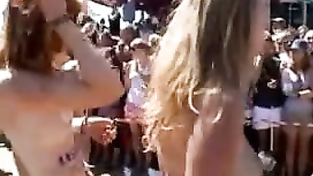 Nude blonde and redhead women dancing topless at Roskilde nude festival crowd