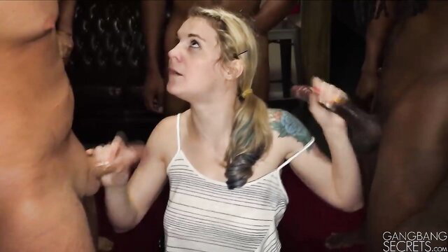 Blonde tattooed girl surrounded by muscular men in intense gangbang scene