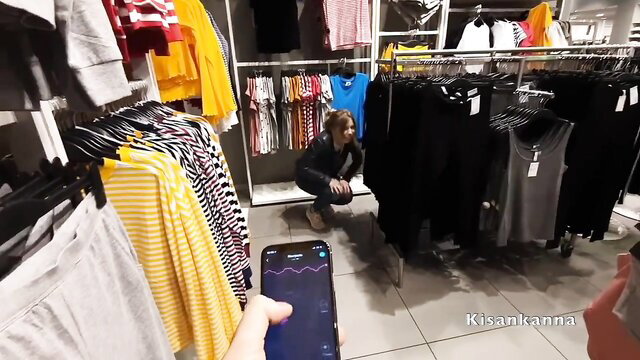 Blonde woman squats in clothing store, phone shows arousal graph