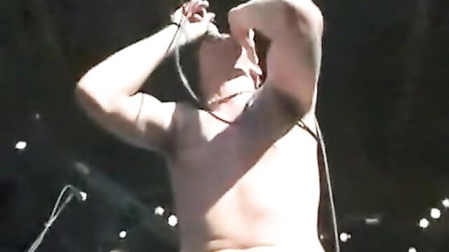 Shirtless muscular man passionately singing into mic on stage