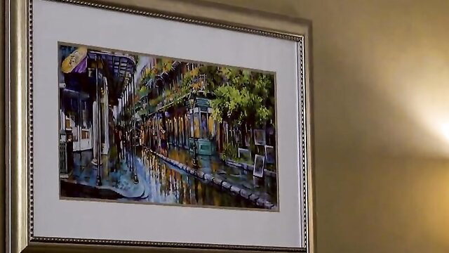 Vibrant painting of rainy New Orleans street in ornate gold frame on wall