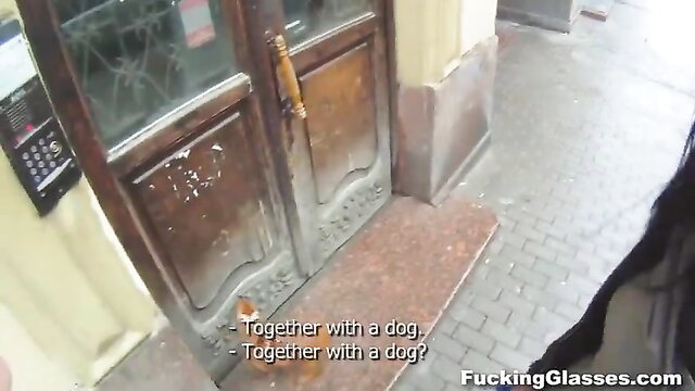 Brunette teen stands by apartment door with dog, teasing outdoor exposure