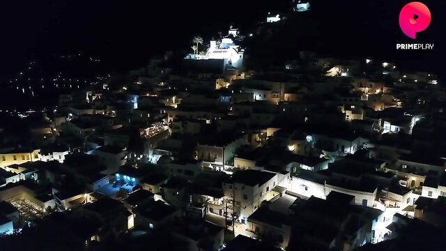 Aerial night view of lit Greek village houses on hill, Primeplay hot web series thumbnail