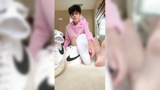 Cute Asian twink in pink hoodie shows dirty white socked soles and Nike sneakers