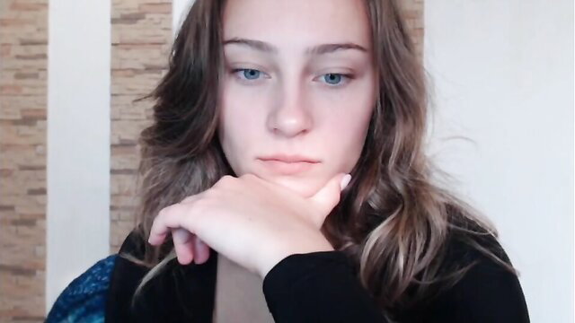 Sexy blue-eyed brunette teen in black cardigan ponders seductively