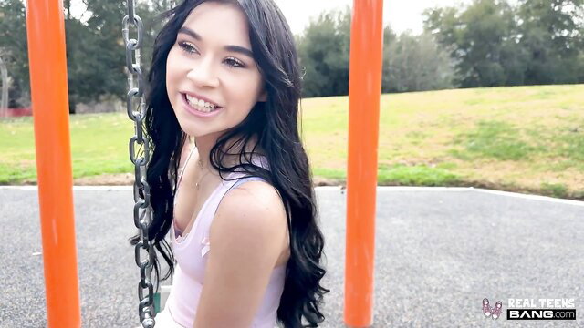 Asian teen Delilah Dagger smiling on swing in tight tank top