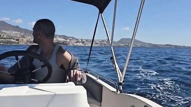 Muscular Latino man shirtless steering speedboat at sea, hot outdoor cruise