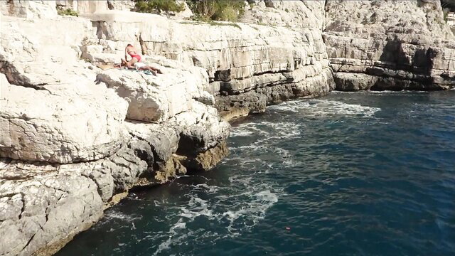 Agathe de La Boulaye topless sunbathing on rocky cliff by sea