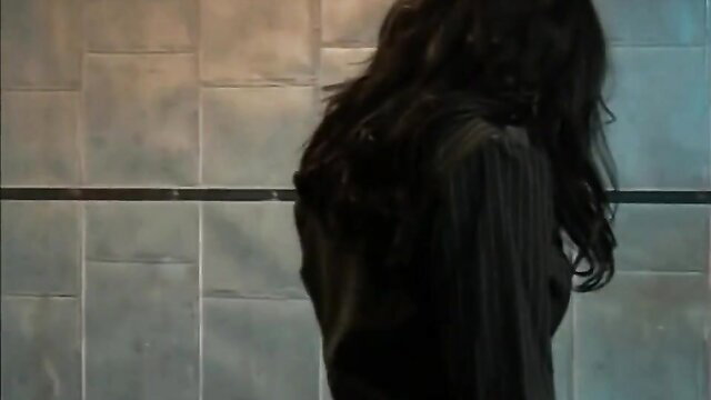 Silhouette of long-haired woman in dark dress against tiled wall