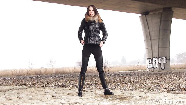 Jessica Bell in black leather jacket, pants, boots under bridge