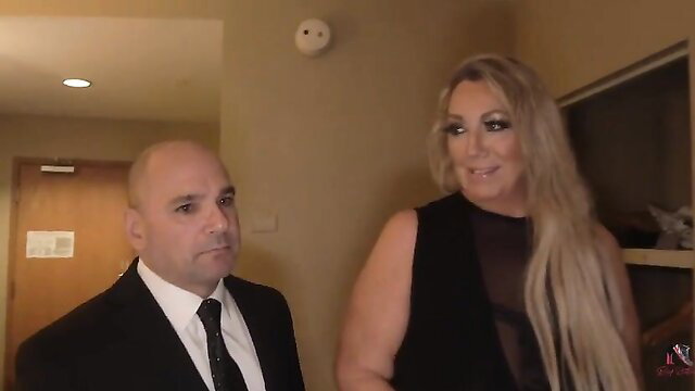 Bald suited man with busty blonde MILF slut in sheer black dress