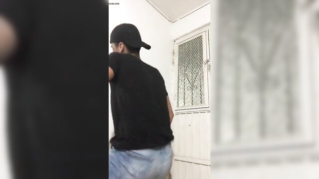 Latino man in black tee and jeans dances teasingly from behind