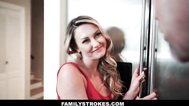 Blonde bombshell in red dress flirts with man by fridge in taboo family scene