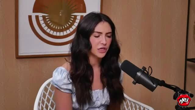 Jane Wilde singing passionately in off-shoulder top on podcast