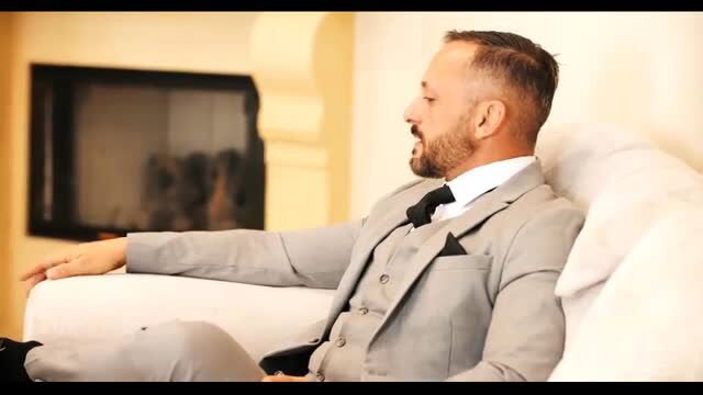 Dorian Del Isla in elegant gray suit lounging seductively