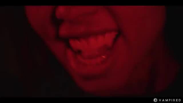Close-up of Canela Skin showing vampire fangs in red light