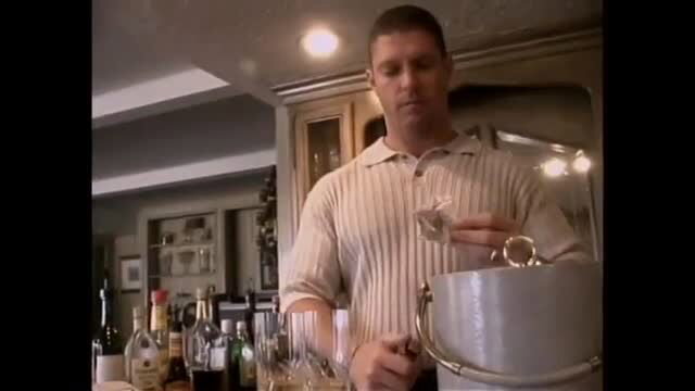 Man in striped polo shirt holding metal bucket in kitchen