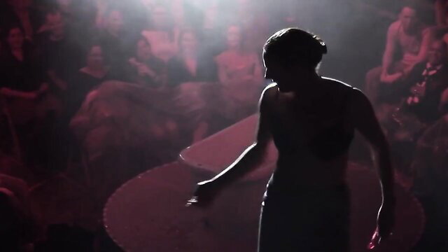 Silhouette of sexy woman performing magic striptease on stage