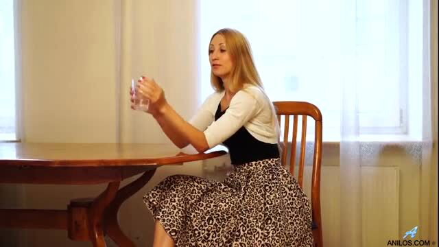 Milian Mae in leopard skirt holds glass, sexy seated pose
