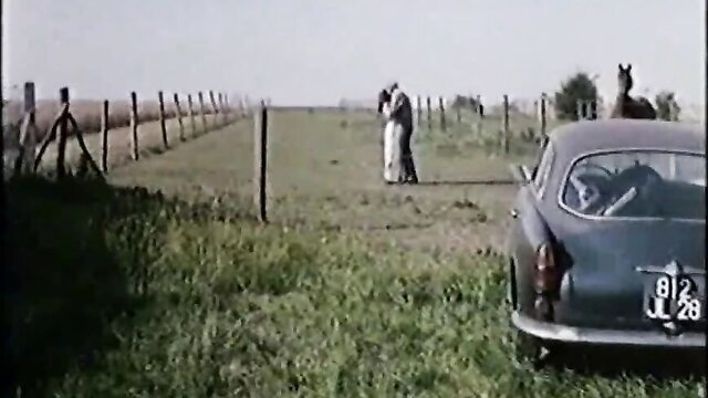 Diane Dubois embraces man by vintage car in field, Lickings 1978