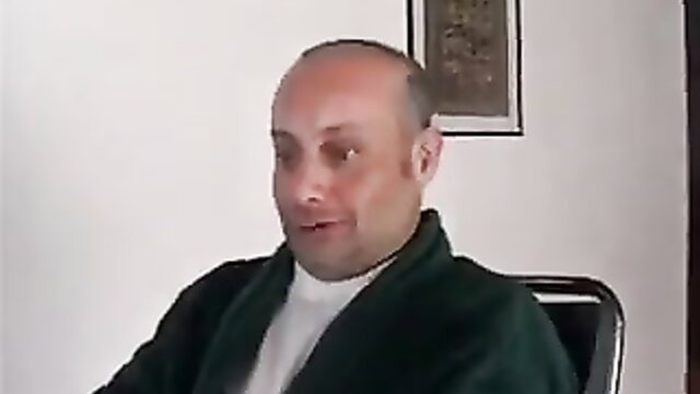 Bald middle-aged man in green robe at intimate clinic POV