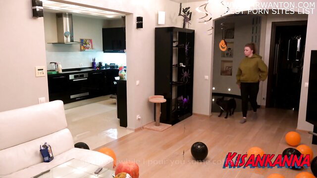 Kisankanna in Halloween outfit with black cat, cozy apartment scene