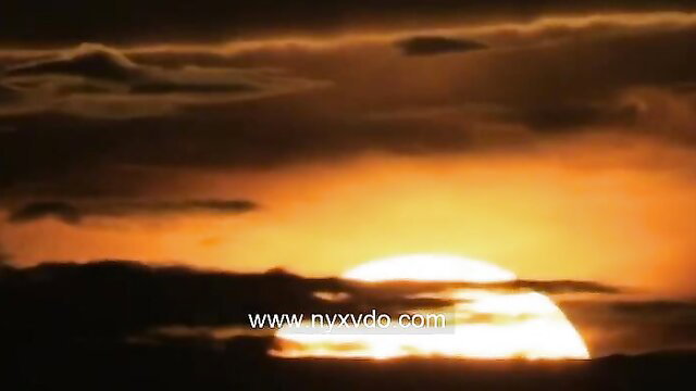 Stunning sunset sky with glowing orange sun and dark clouds
