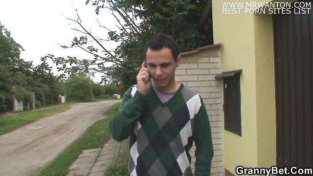 Man on phone in argyle sweater outside grannybet house