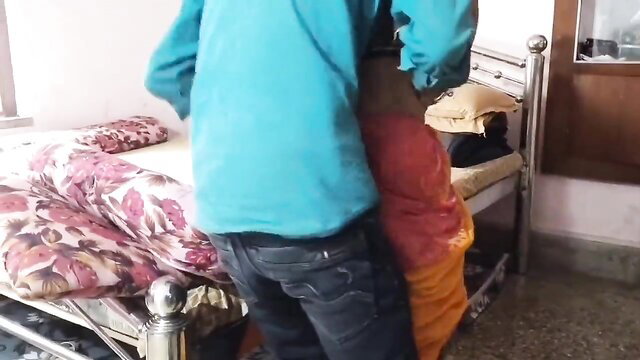 Man in blue shirt grabs maid's hips from behind by bed