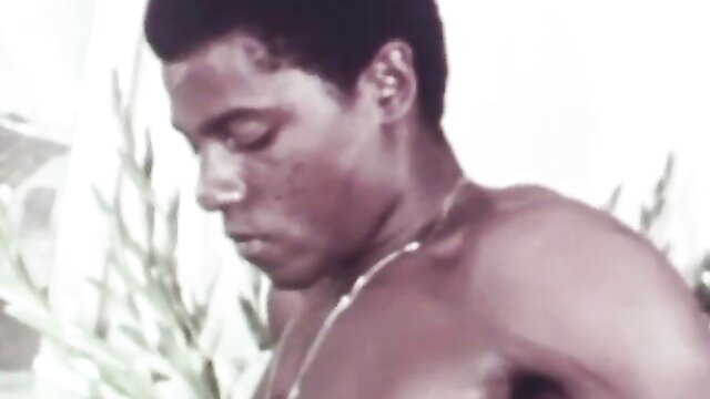 Vintage black stud shirtless profile in foliage, muscular build