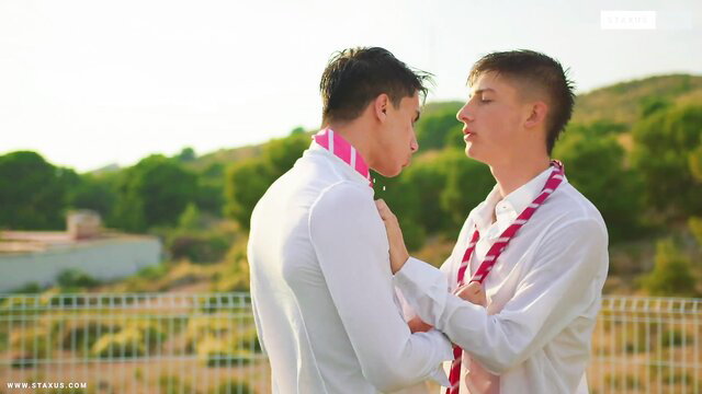 Two hot twinks in white shirts and colorful sashes share intense outdoor eye contact