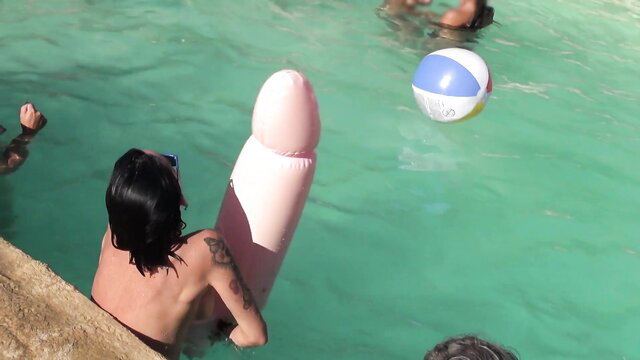 Pool party with giant pink dildo float and topless guy at libertine club