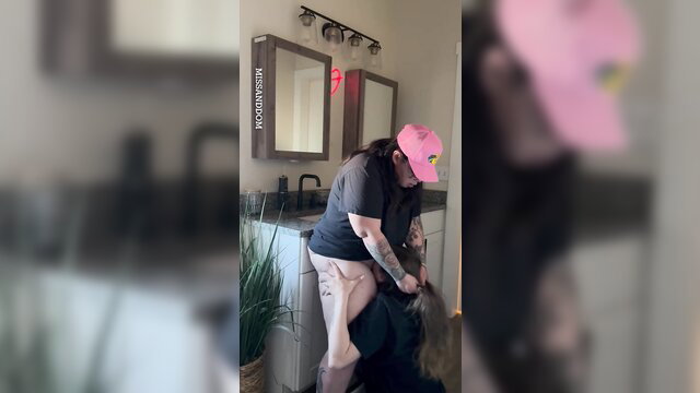 MissAndDom bends over sink in pink trucker hat, thick thighs exposed